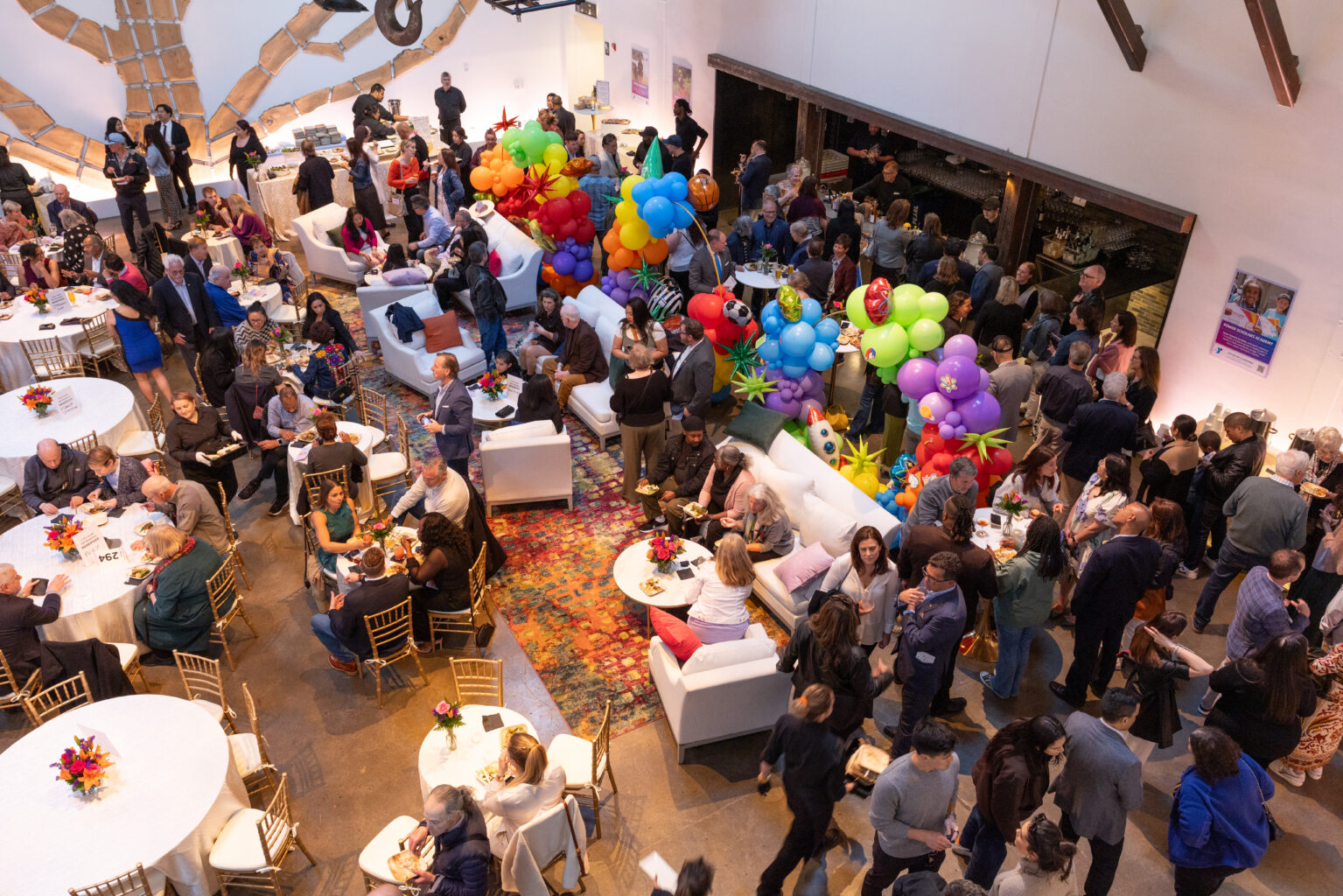 Room full of people seated and standing, talking with each other at an event.